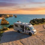 Camping-car stationné sur une falaise surplombant la mer au coucher du soleil au Portugal.