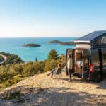 Un couple profite de la vue sur la mer Adriatique depuis leur camping-car aménagé stationné sur une colline.